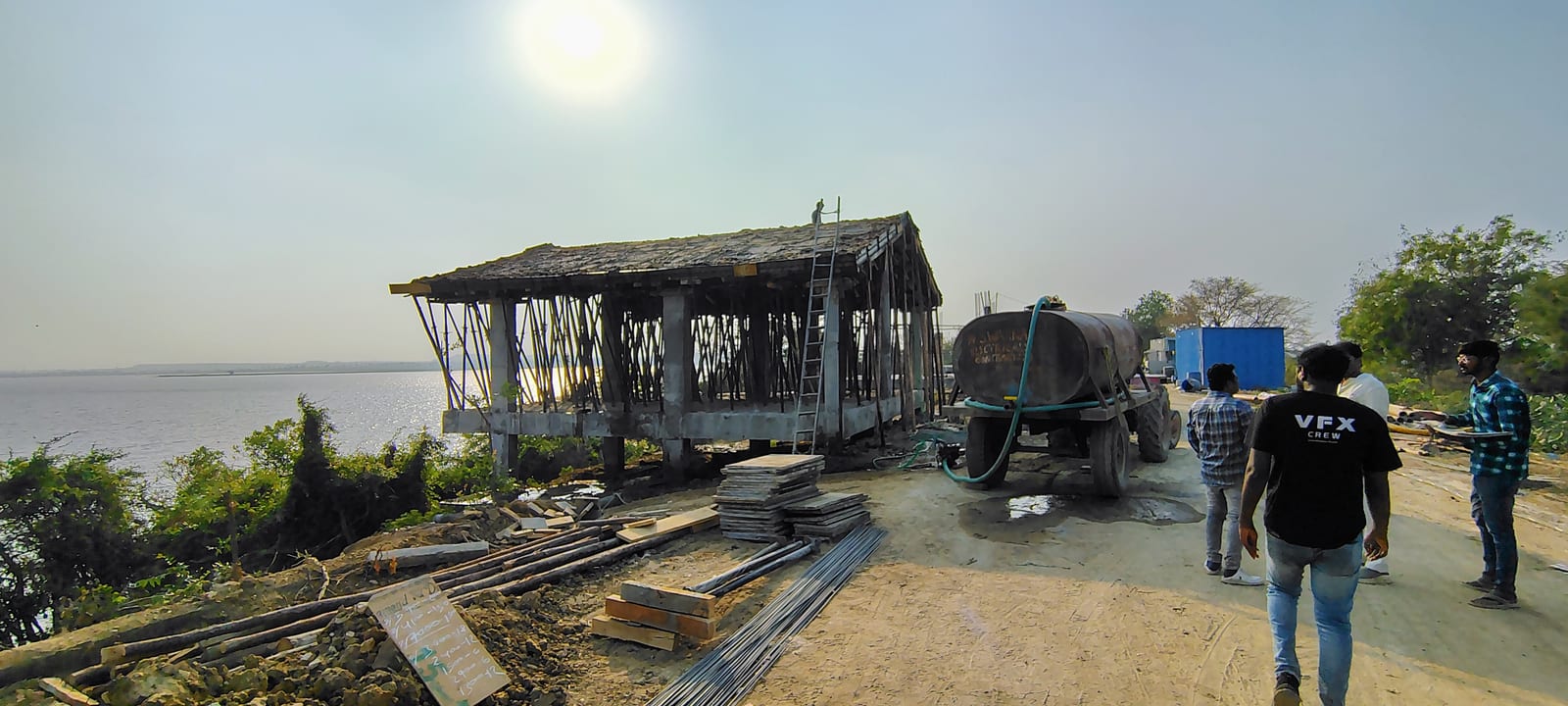 Riverside RCC pavilion under construction with water tanker and site crew