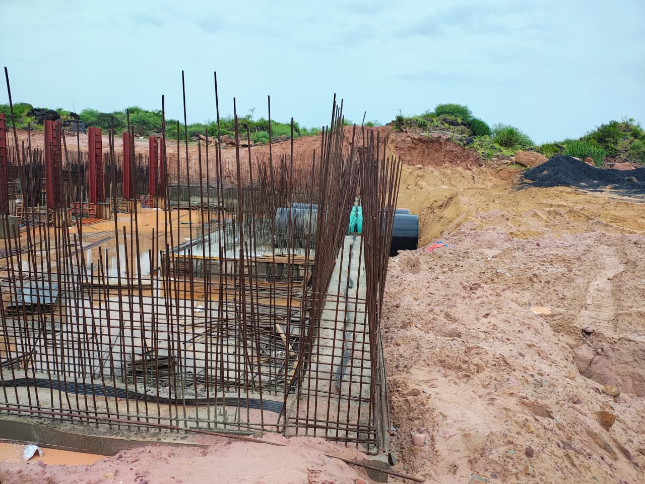 Arched irrigation structure reinforcement rising above a stone masonry retaining wall