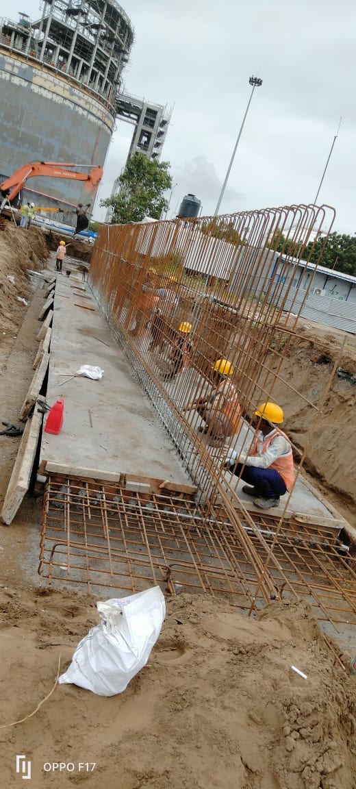 Foundation and pipe trench with reinforcement cages beside a spherical storage tank